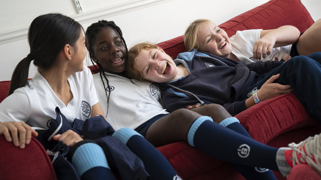 Four girls sat on a couch in the Junior House common room
