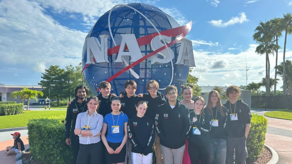 Bea and her teammates stood in front of the NASA sign.
