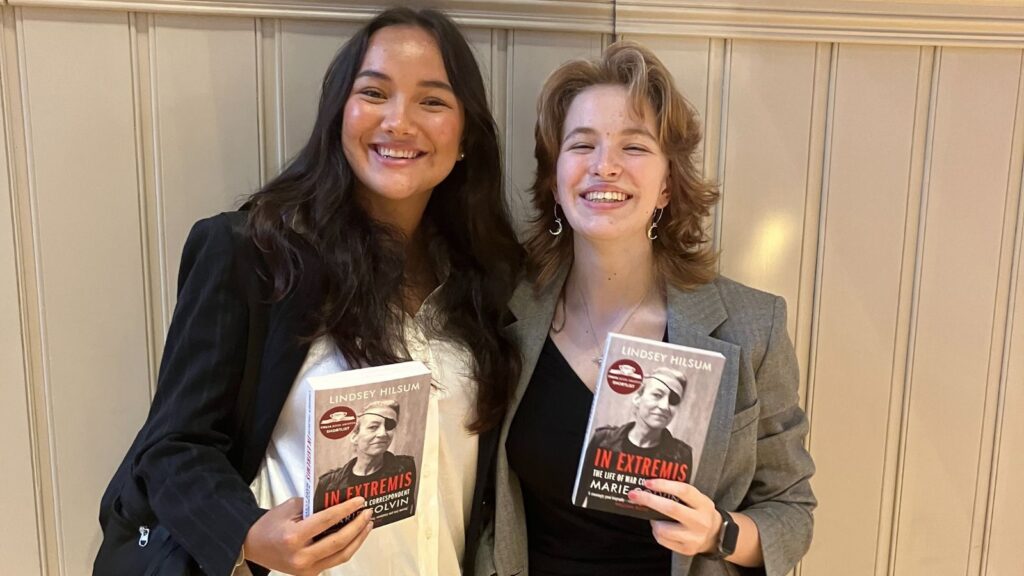 Two girls smiling whilst holding a copy of Lindsey Hilsum's book 'In Extremis'.