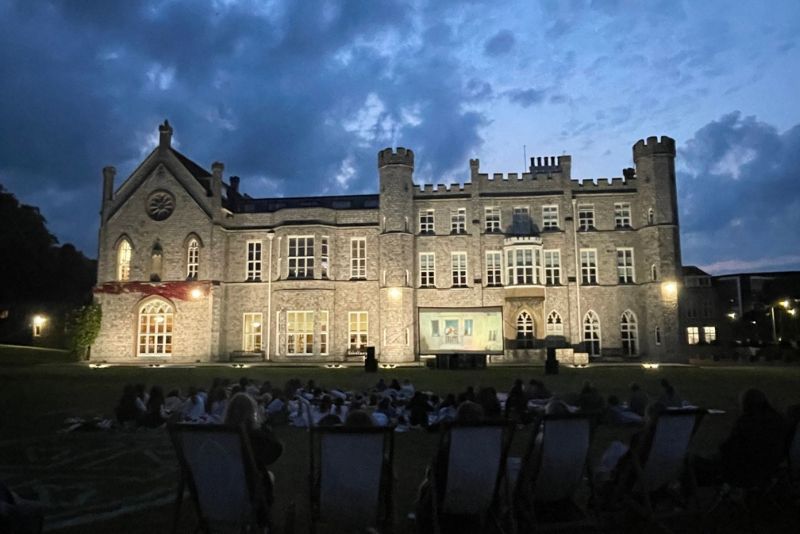 Pupils sat on deck chairs and picnic blankets, watching a film on a large screen in front of the Abbey at night.