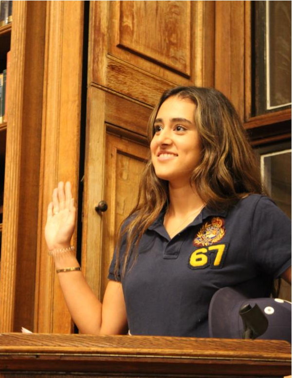 A pupil stood behind a lectern whilst raising her right hand.