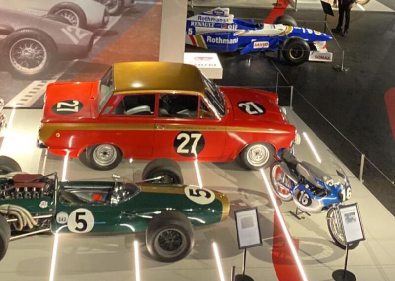 A green and red car in a glass case at a museum.