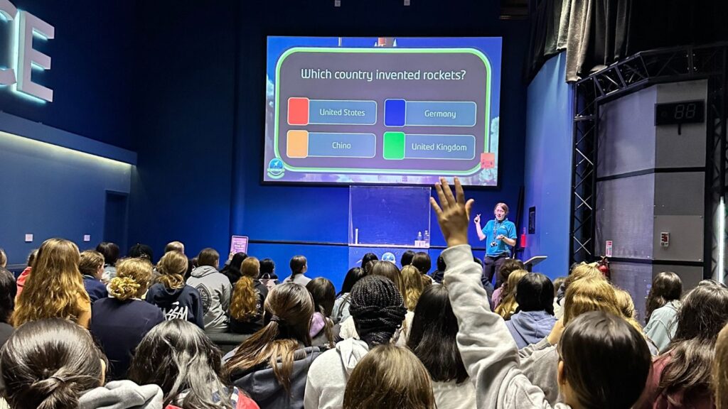 Pupils are sat participating in a quiz. The multiple choice option for the question 'Which country invented rockets?' are on screen.