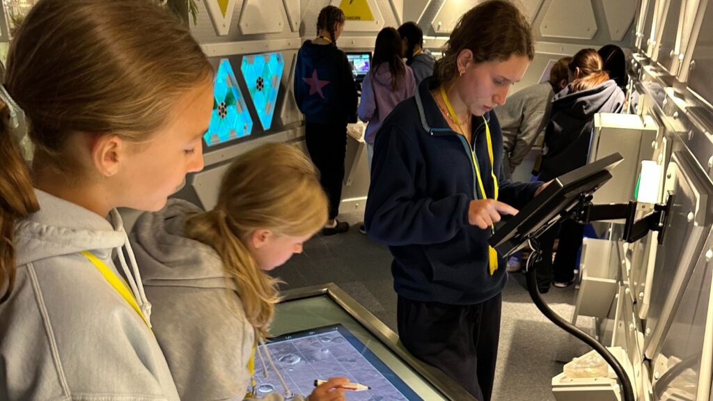 Pupil writing and swiping on interactive screens.