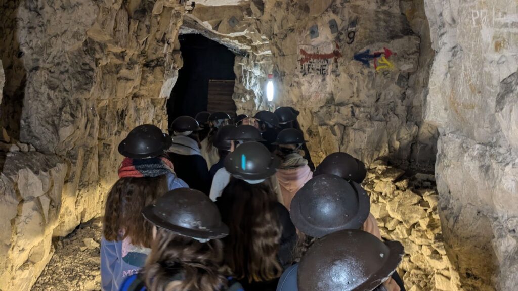 Pupils walking through tunnels Wellington Quarry Museum whilst wearing WW2-style helmets.