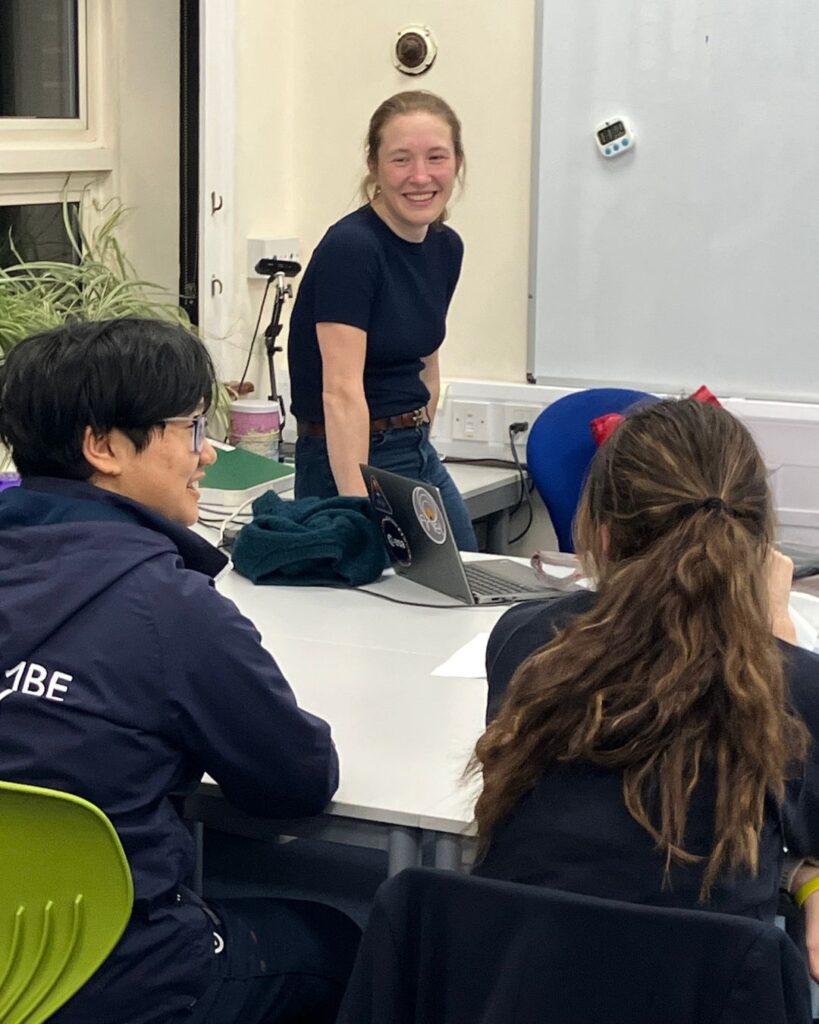 Speaker stood at the front of the class, laughing with two Wycombe Abbey pupils.