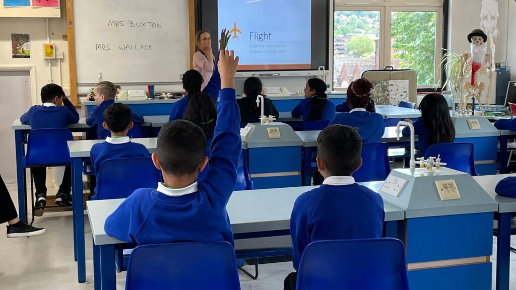 Mrs Buxton is teaching a class of primary pupils about flight. One boy has his hand up.