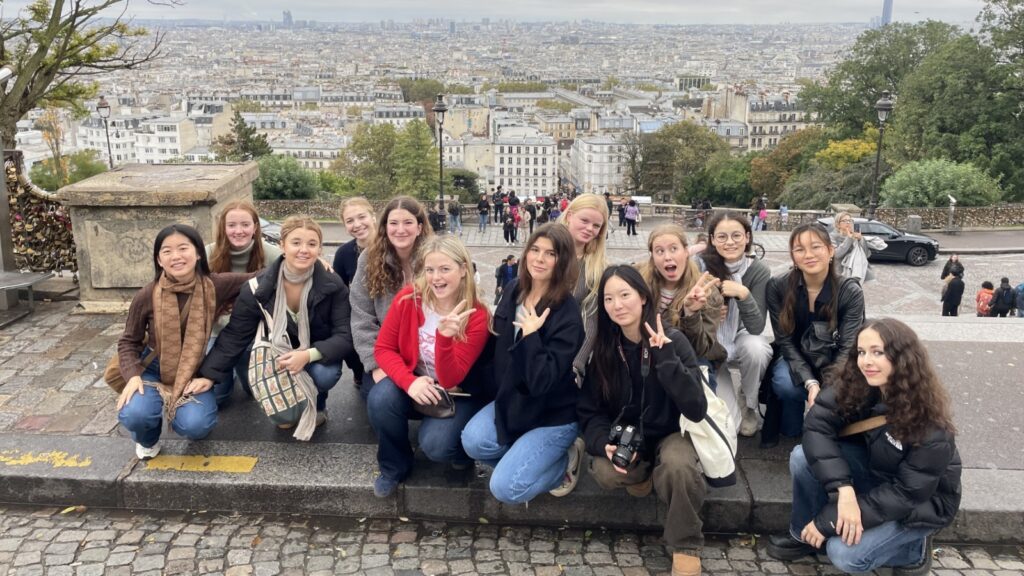 Pupils squatting on the floor with the view of Paris behind them.