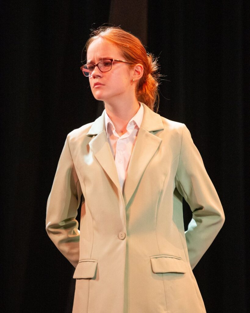 A Wycombe Abbey pupil with a cross face and arms behind her back.