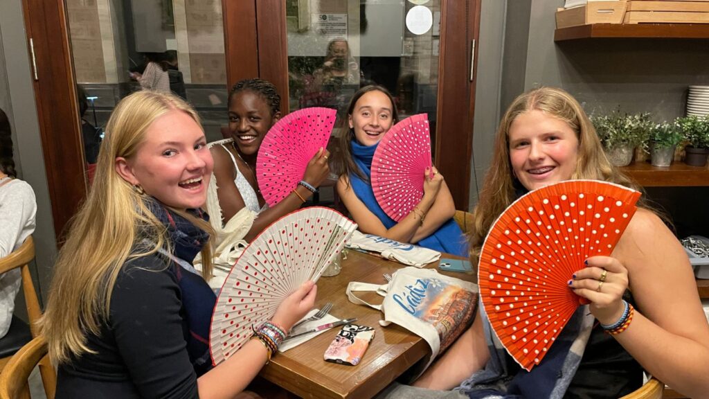 Four pupils smiling with traditional Spanish fans.
