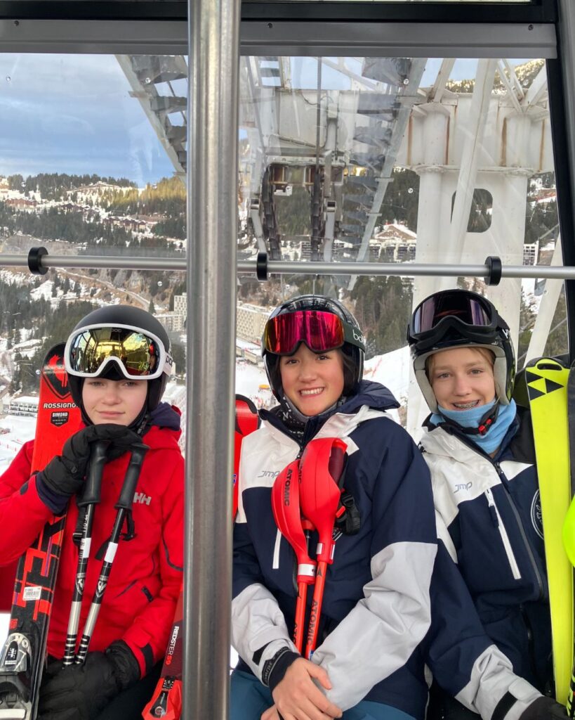 Three pupils sat on a ski lift.