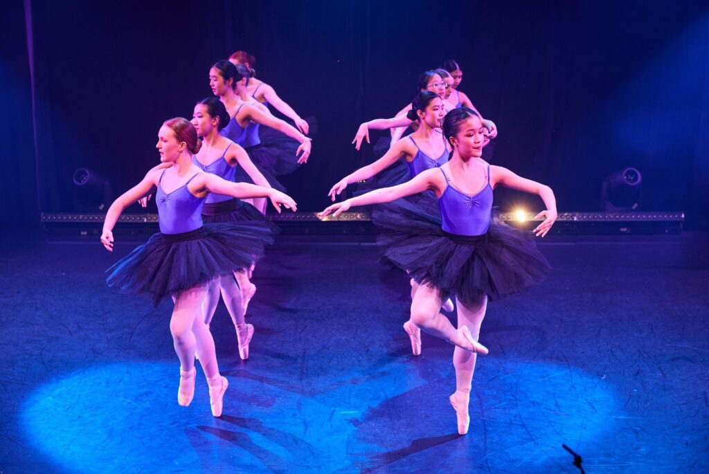 Pupils dancing on stage in blue leotards and tutus.