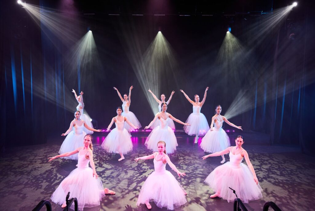 Pupils dancing on stage in baby pink tutus and leotards.
