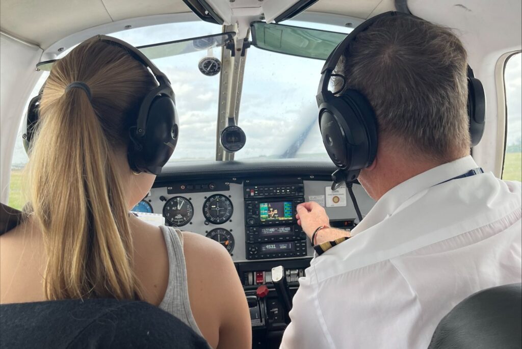 Avalon in the cockpit. She and her instructor are wearing headphones.