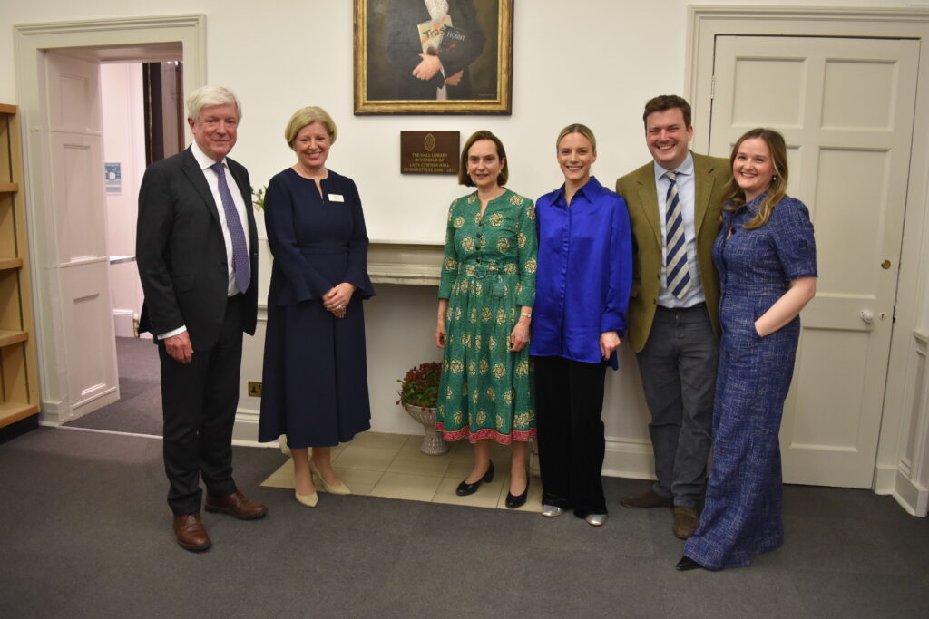 Lady Cynthia Hall, her family, and Jo Duncan stood below Lady Cynthia Hall's plaque and portrait.