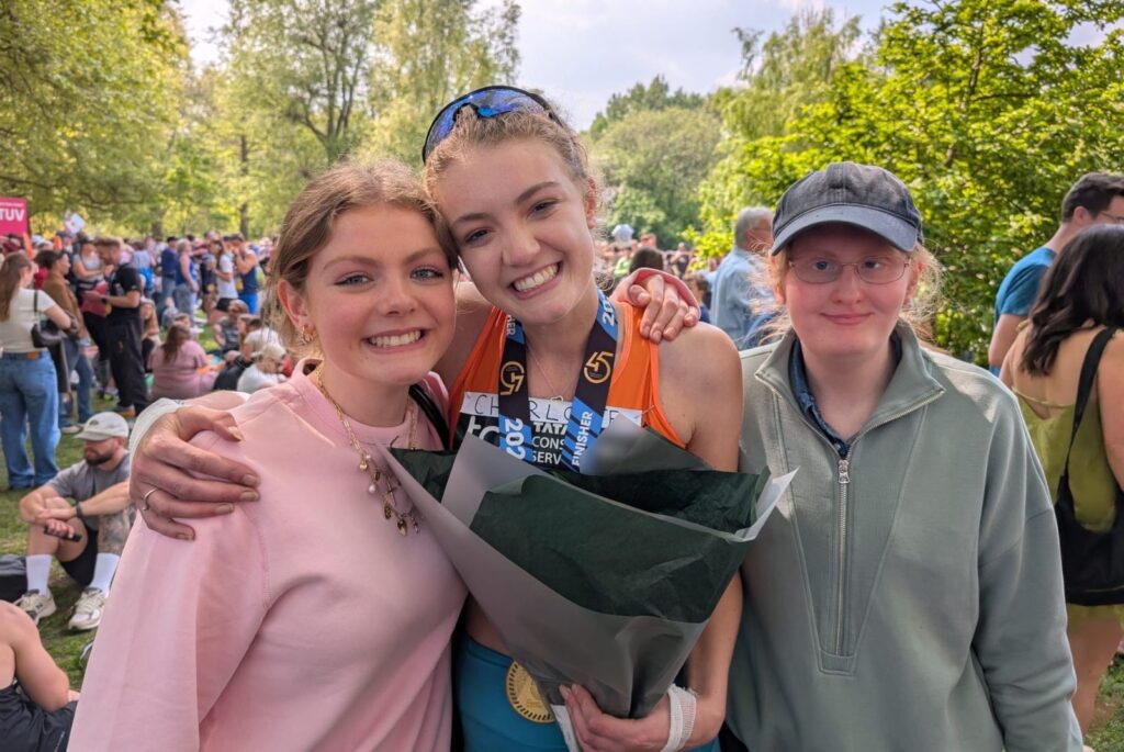 Charlotte holding a bouquet of flowers with her family either side of her.