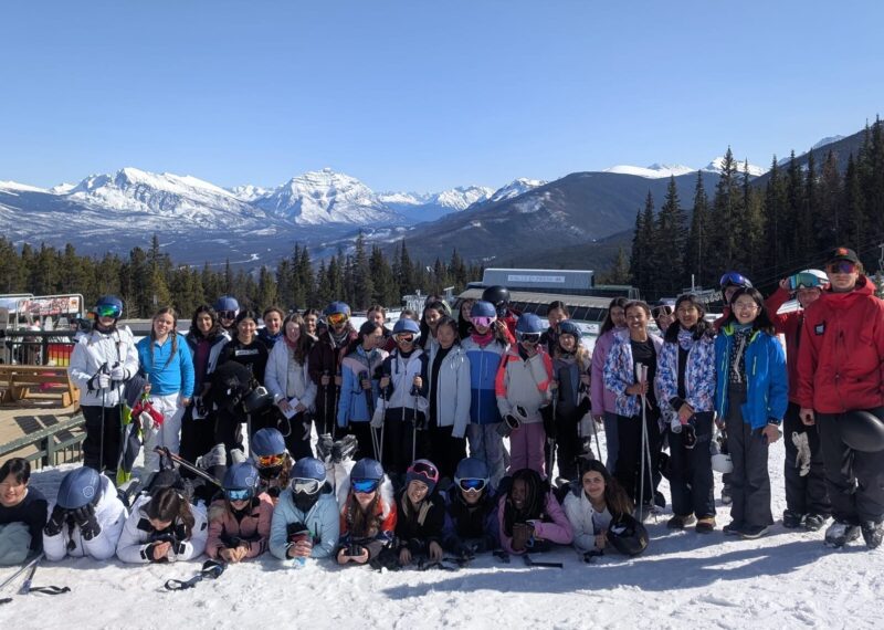 Pupils stood together at the bottom of the mountain with their skis.