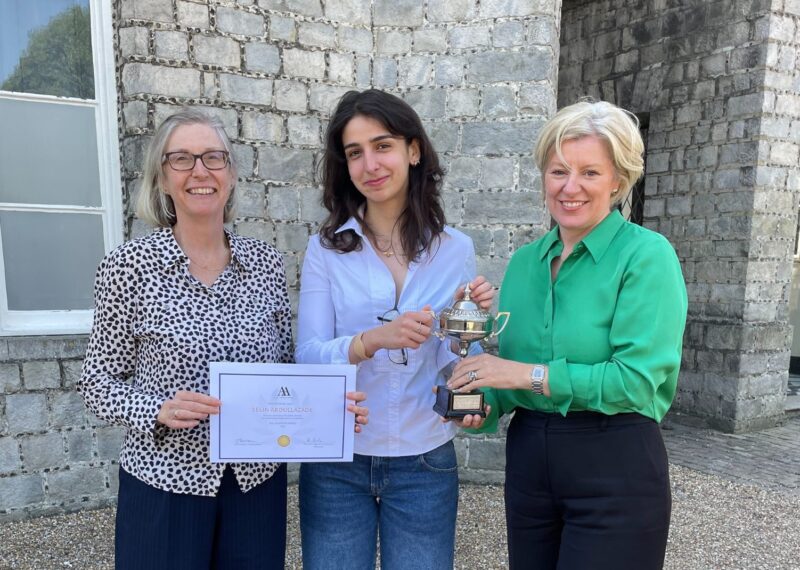 Mrs Kiln, Selin, and Mrs Duncan stood outside of School with Selin's certificate and trophy.