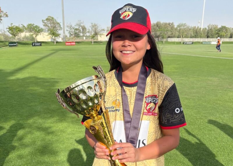 Ceci wearing a Vipers cap, wearing hew hold medal, and holding a trophy.