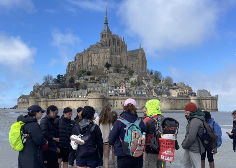 Pupils stood on the beach looking up at Mont Saint Michel.