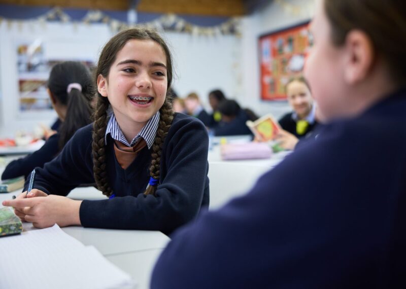 A girl holding a pen, laughing with her friends.