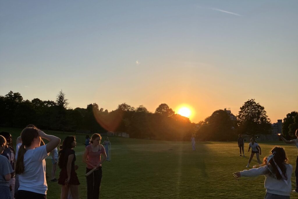 Pupils playing rounders during sunset.