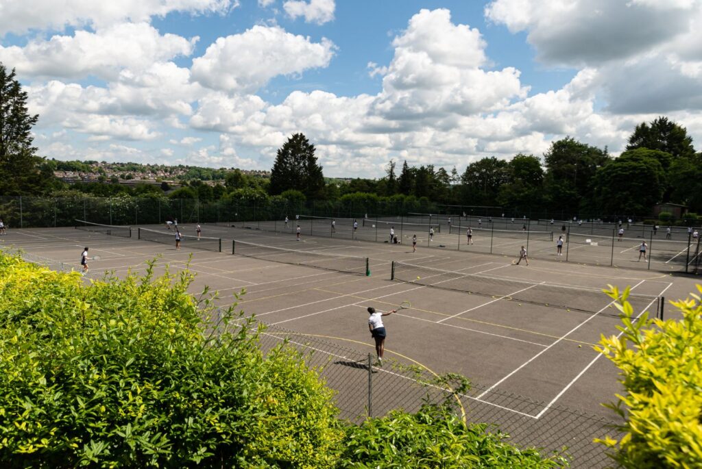 Pupils playing tennis on the tennis courts.