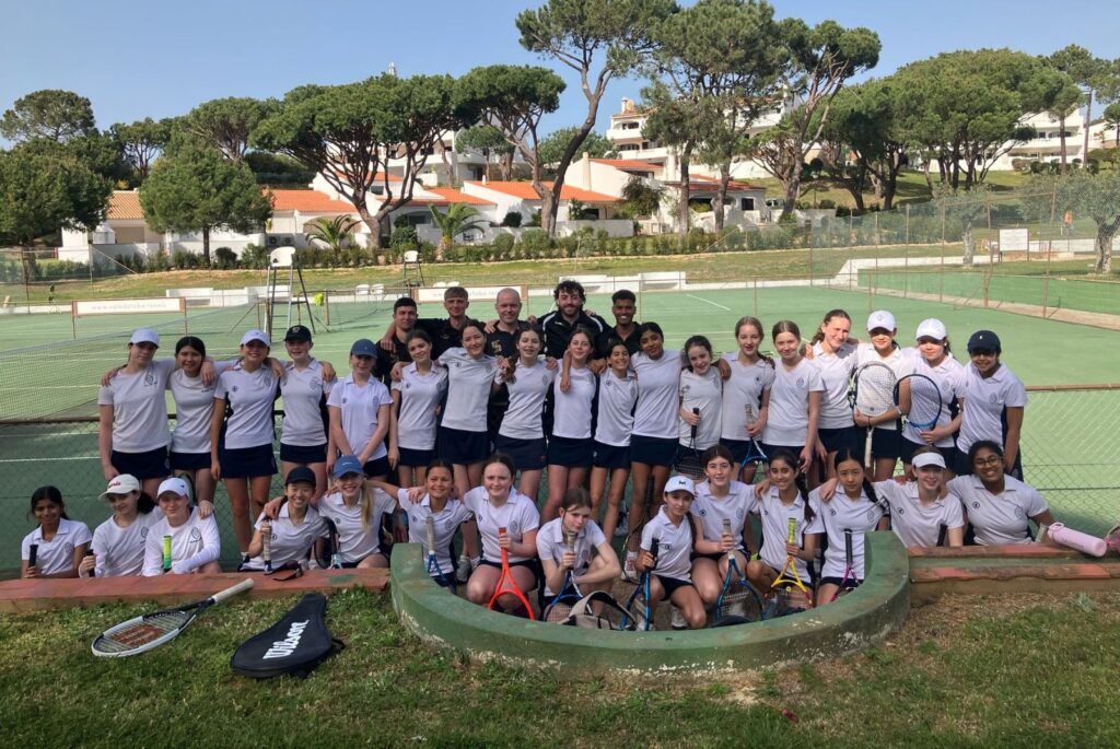 Pupils and their coaches beside the tennis courts.