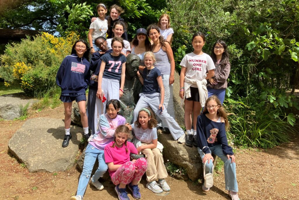 UIII pupils stood surrounding a statue.