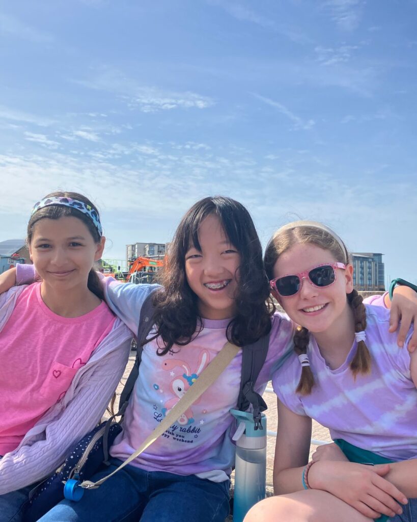 Three UIII pupils sat on a wall with their arms around one another.