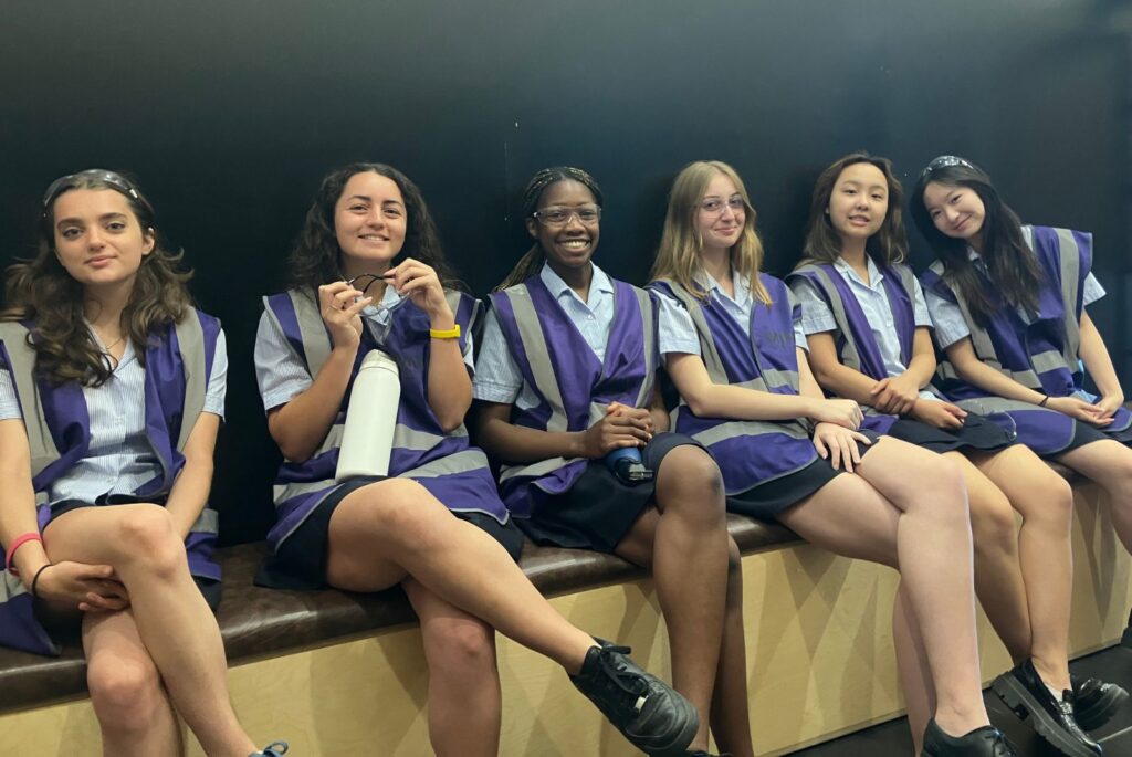 Pupils sat in a line wearing purple hi-vis jackets and safety goggles.