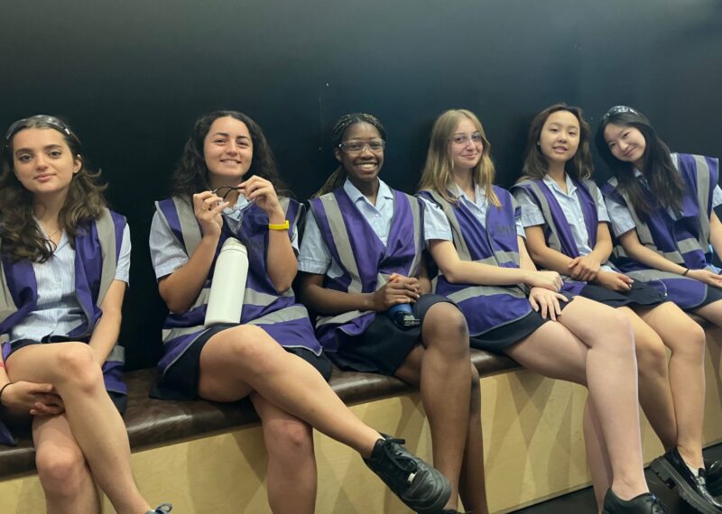 Pupils sat in a line wearing purple hi-vis jackets and safety goggles.