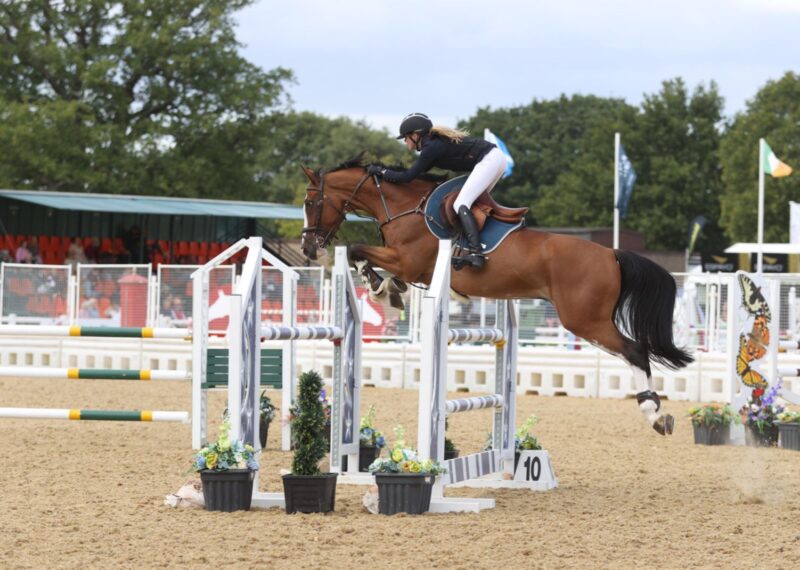 Cassandra jumping over a jump on her horse.