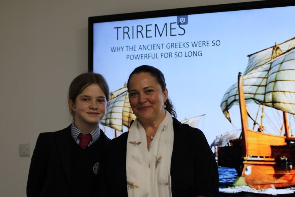 A picture of Charlotte and her mother Laura in front of a photo of a Trireme.