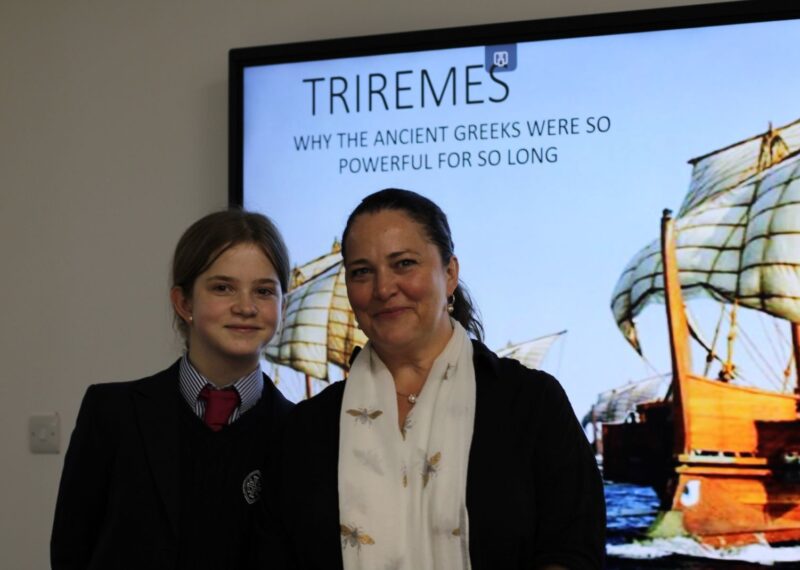 A picture of Charlotte and her mother Laura in front of a photo of a Trireme.
