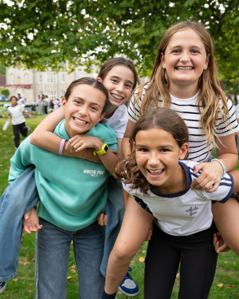 Two pairs of girls giving piggybacks.