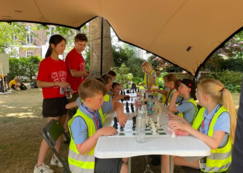 Emma and a fellow CSC ambassador coaching young children play chess.