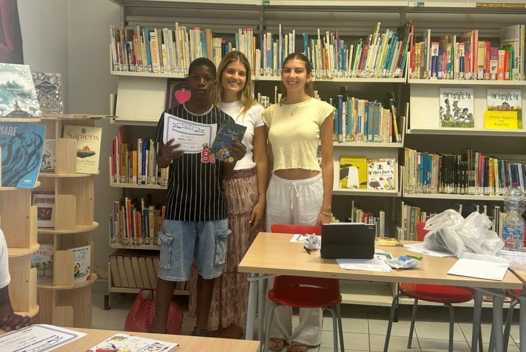Mati, her friend, and one of their students stood in front of a bookcase.