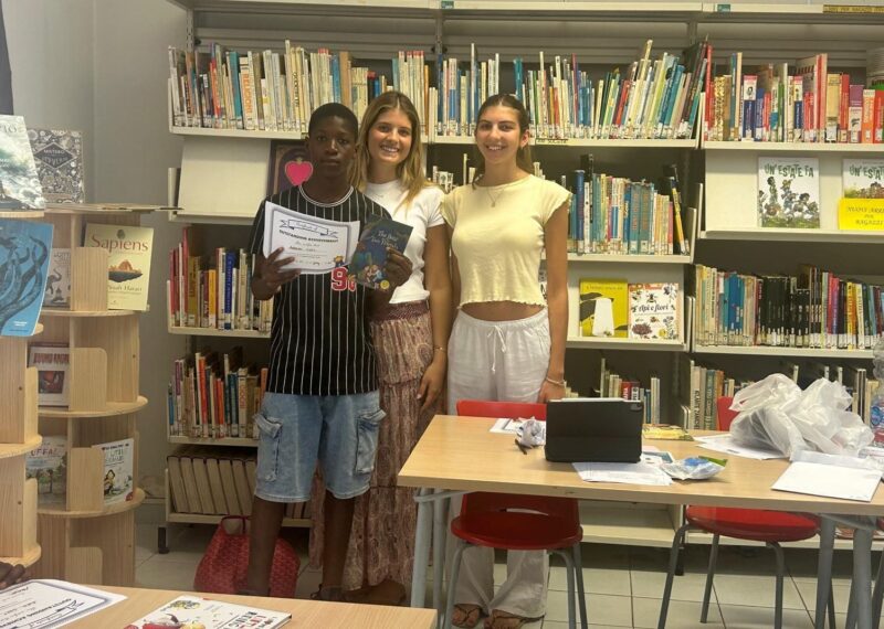 Mati, her friend, and one of their students stood in front of a bookcase.
