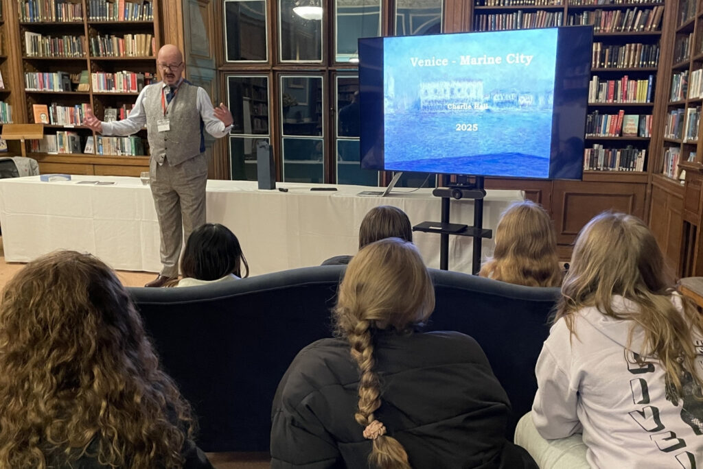 man in library standing in front of power point presentation
