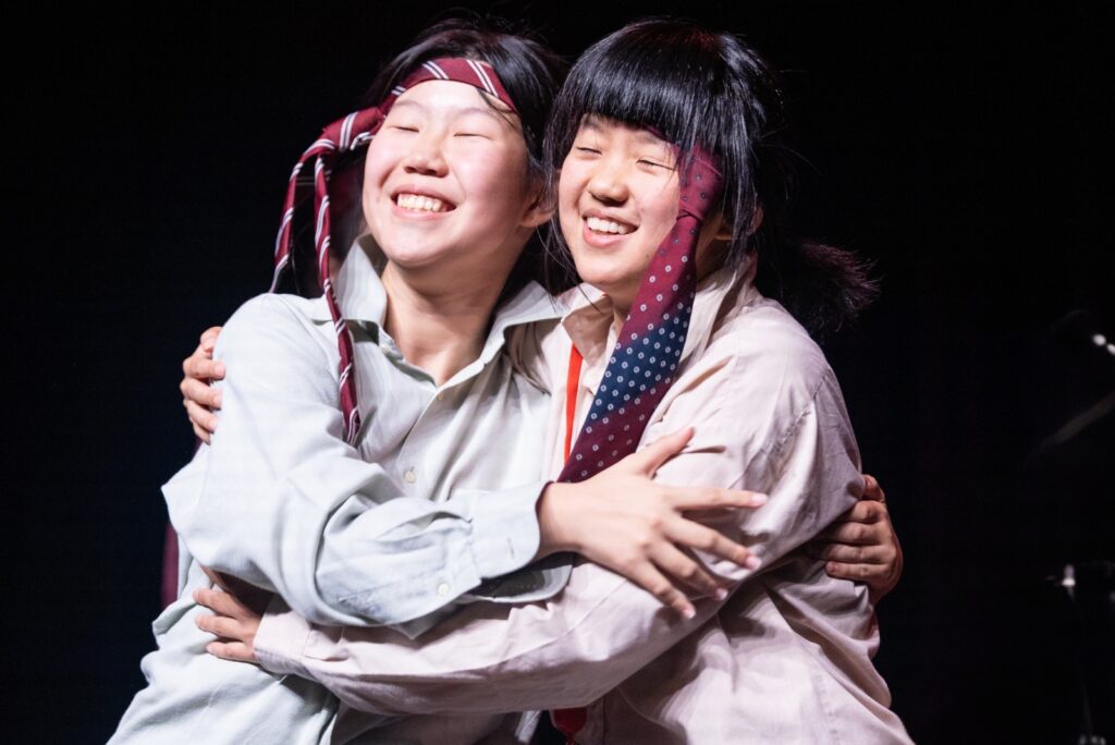 girls with ties on their head hugging on stage